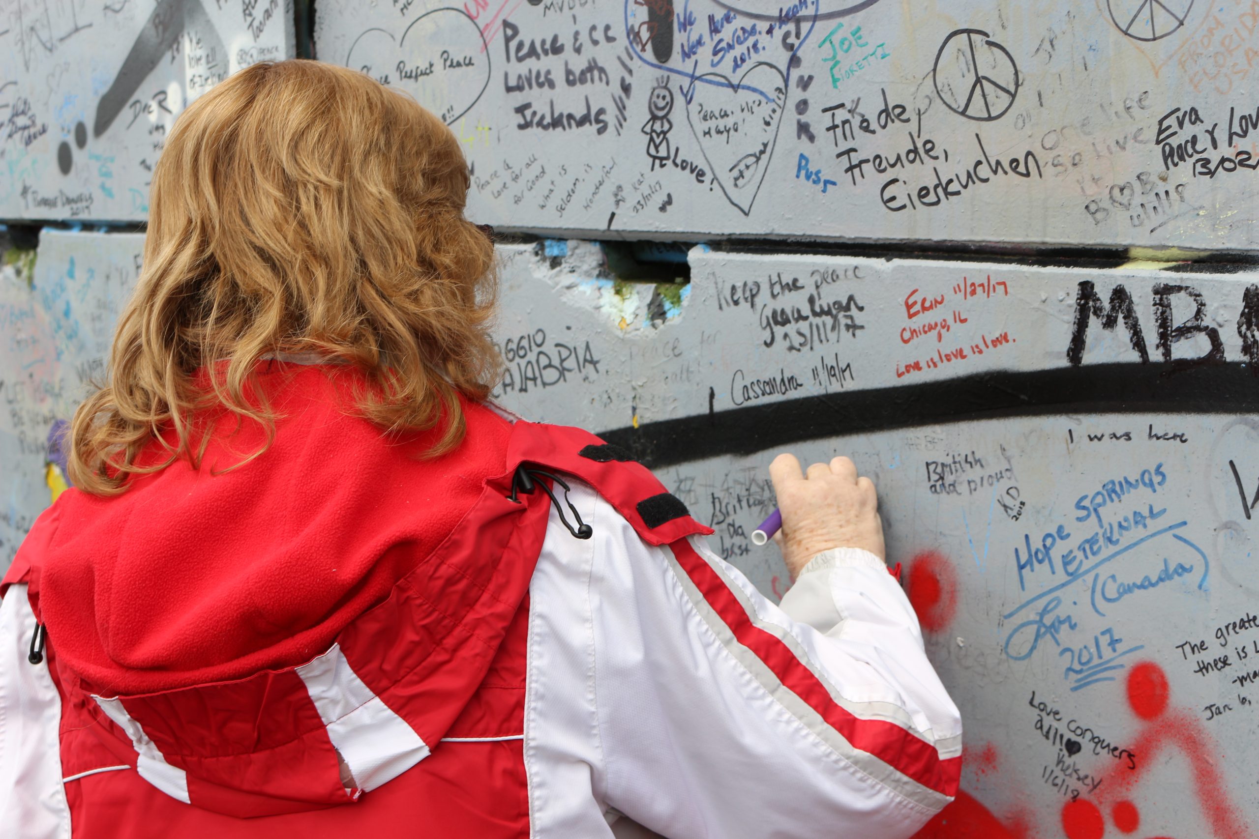 A woman writes on the Peace Wall in Belfast in 2018, commemorating the violence that happened in Northern Ireland.