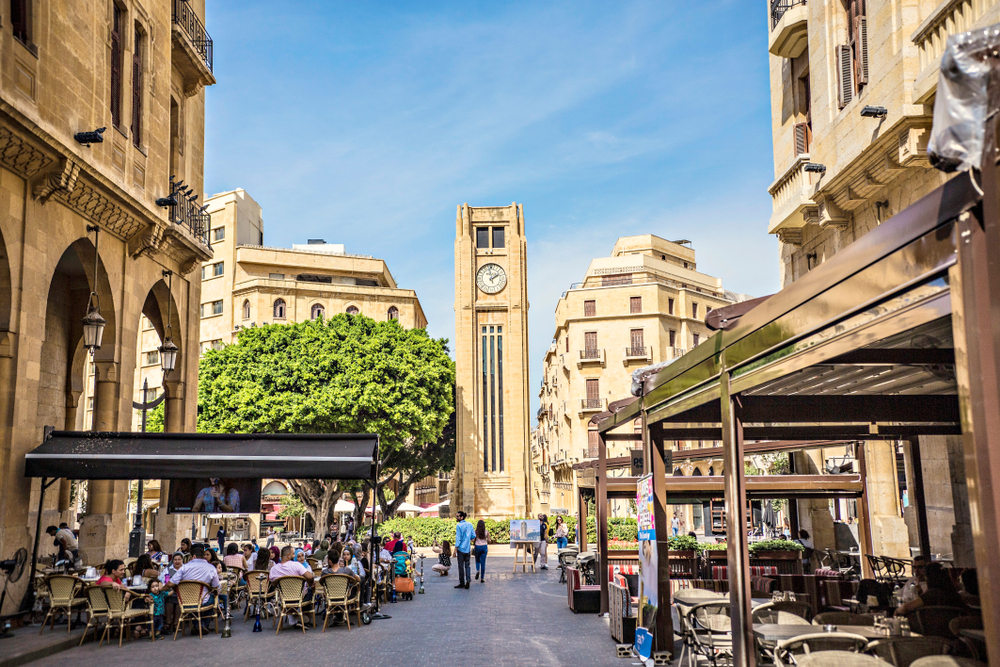 Diners sit outside at a restaurant with a clock tower in the background
